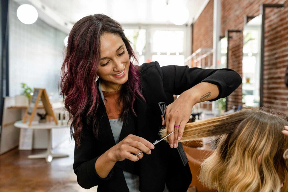 a hairdresser cutting hair with scissors - small business website design diy or pro